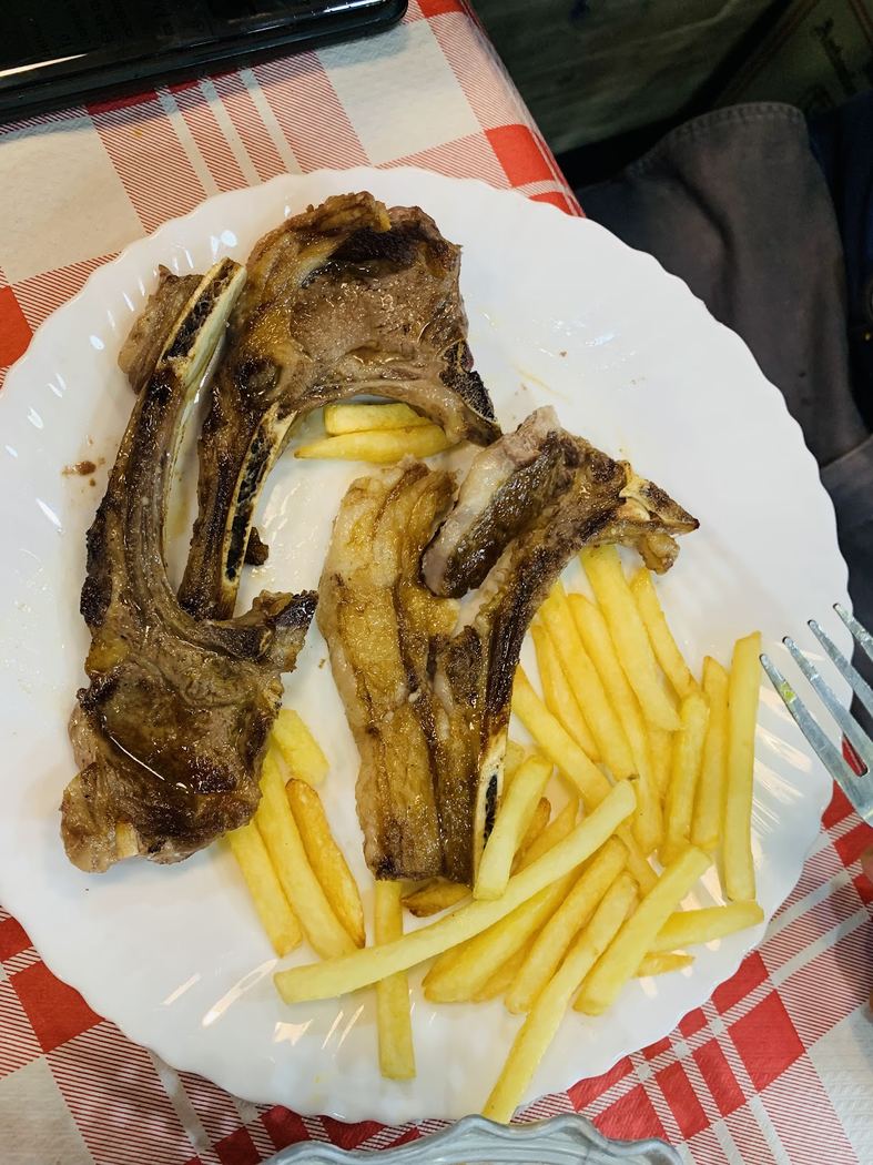Chuletas de cordero a la brasa con patatas fritas, presentadas en un plato.