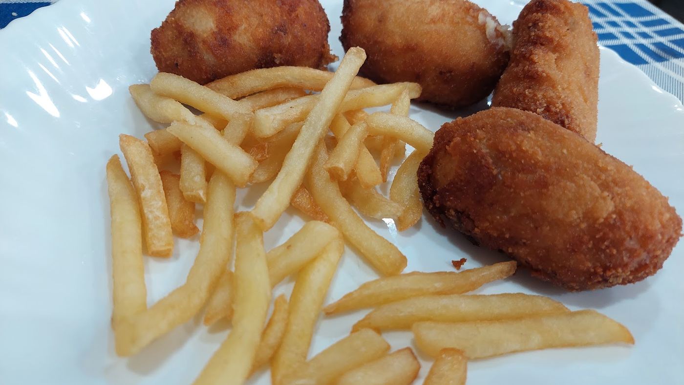 Surtido de croquetas caseras variadas acompañadas de patatas fritas.